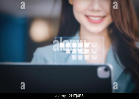 A female entrepreneur or businesswoman showing a smiling face while operating a computer tablet working on a wooden table. Stock Photo