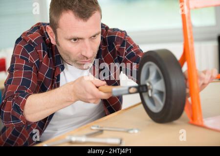 man repairing trolley wheel in workshop Stock Photo