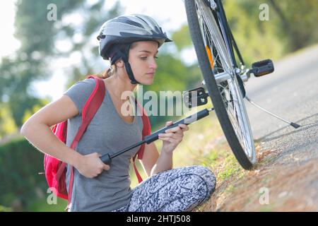 young woman pumping up tire tyre with bike bicycle pump Stock Photo