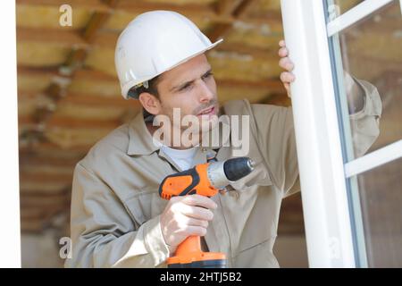 a man drilling window frame Stock Photo