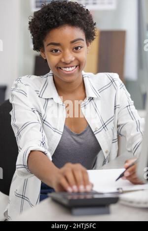 woman calculating invoice with calculator in office Stock Photo