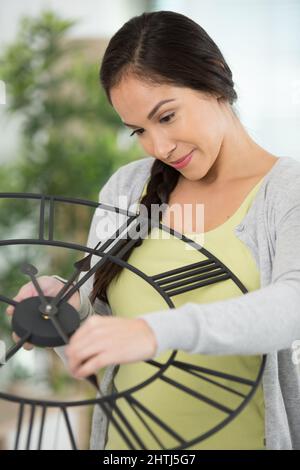 young woman changing battery in a clock on the wall Stock Photo