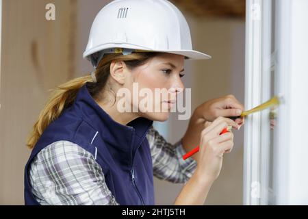 portrait of a woman measuring window frame Stock Photo