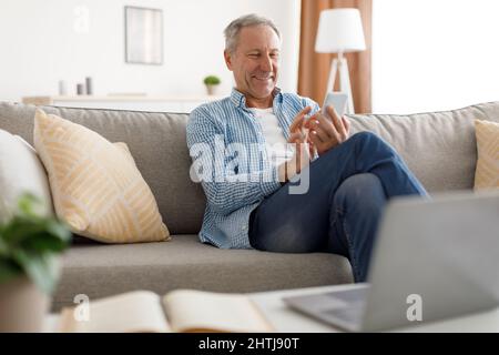 Portrait of smiling mature man using smart phone at home Stock Photo