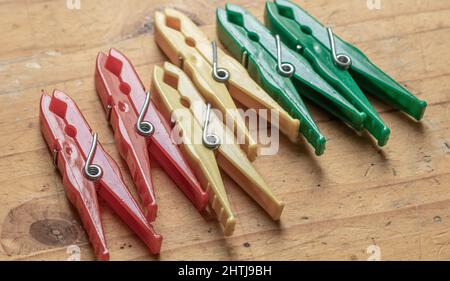 Different classic clothespins made of plastic from a surface with old light wooden structure table Stock Photo