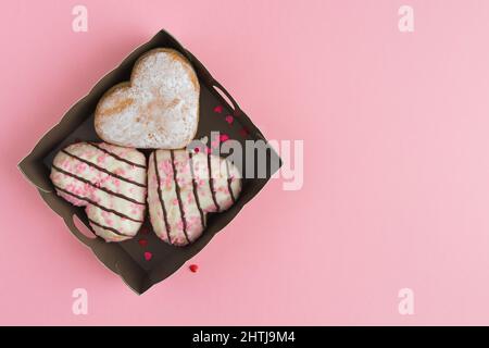 Three heart shaped Donuts inside a box on a pink background. Copy space. Top view. Stock Photo