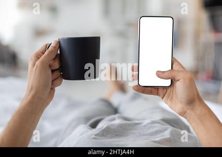 Male Hands Holding Smartphone With Blank Screen And Cup Of Coffee Stock Photo
