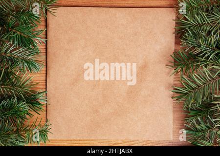 dark green lush pine fir branch frame on light brown wood and recycled brown paper background fir leaves. Christmas tree or holiday card design for ec Stock Photo