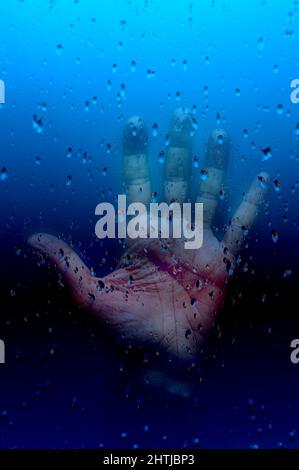 open hand behind a glass with water drops Stock Photo