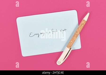 Motivational text 'Every day is a fresh starts' on blue paper note on pink background Stock Photo