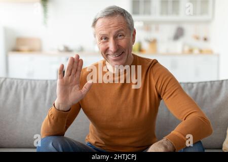 Greeting Concept. Mature man waving hand at camera Stock Photo