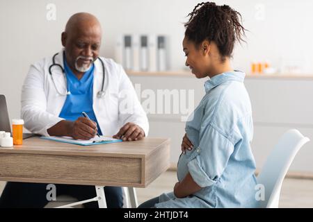 Male doctor consulting young smiling pregnant woman Stock Photo