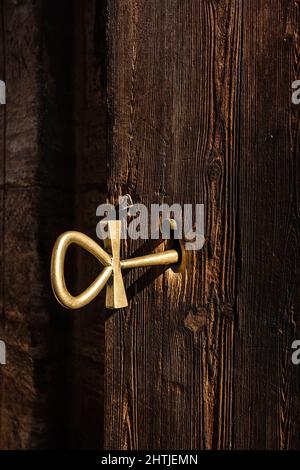 Golden key in lock of shabby wooden door of aged house located on street of Egypt on sunny summer day Stock Photo