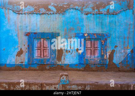 Full frame facade of weathered blue painted house with shabby wall and small windows located on street in town Stock Photo