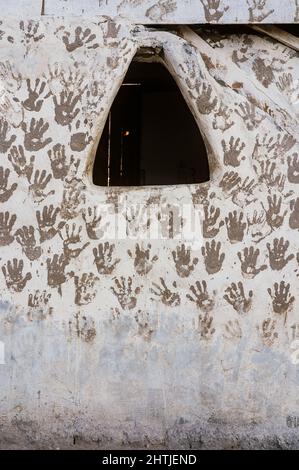 Abundance of handprints on shabby white wall of typical weathered building with small triangular window located on street of Egypt Stock Photo