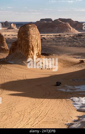 From above suv automobiles driving near shabby chalk rocky formations located on sandy ground in white desert protected area on sunny day in Egypt Stock Photo