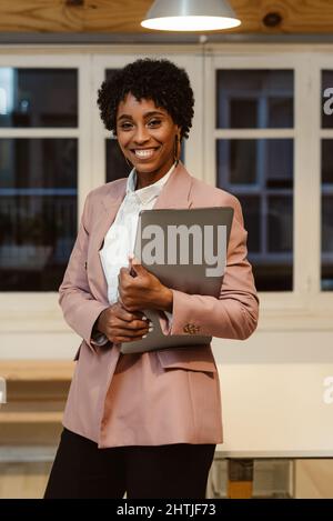 cheerful African business woman with laptop computer on white ...