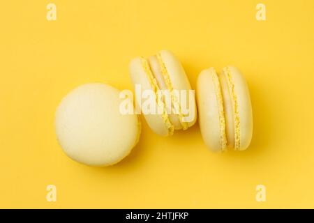 Sweet lemon flavored macarons with tasty filling served on yellow background in light room Stock Photo
