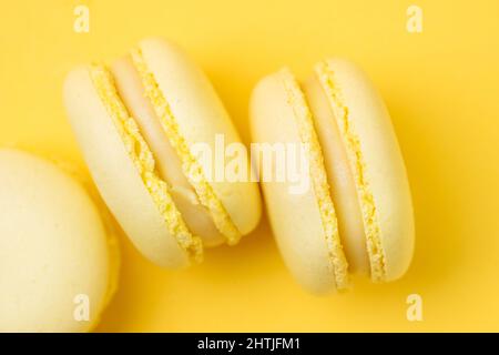 Sweet lemon flavored macarons with tasty filling served on yellow background in light room Stock Photo