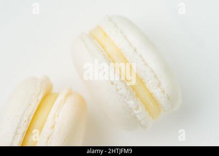 Top view of tasty round shaped vanilla flavored macaroons with sweet yellow filling placed on white background in light room Stock Photo