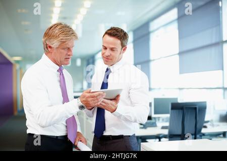 Executives using tablet PC. Handsome business man with colleague using tablet PC in office. Stock Photo