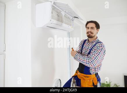 Young repairman or technician with screwdriver fixing problems with air conditioner Stock Photo