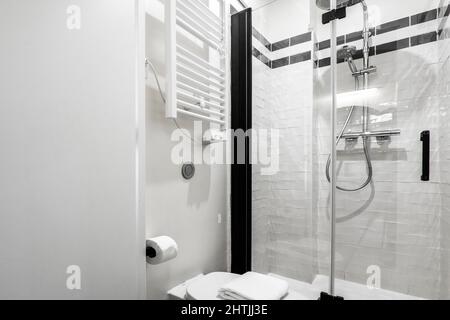 Shower cabin with glass screen and white radiator for towels attached to the wall Stock Photo