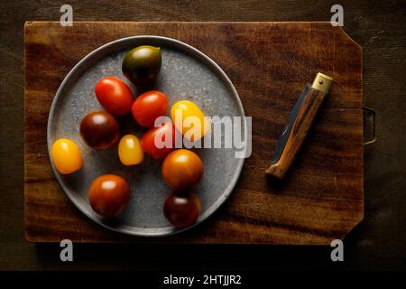 Organic cherry tomatoes on an old wooden cutting board, Italy, Europe Stock Photo