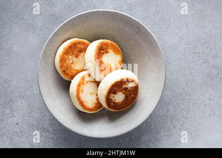 Syrniki, cottage cheese fritters on grey ceramic plate, top view. Breakfast food Stock Photo