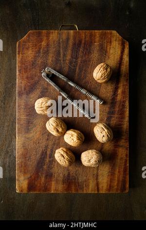 Walnuts and old nutcracker on a vintage cutting board, Italy, Europe Stock Photo