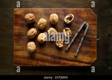 Walnuts and old nutcracker on a vintage cutting board, Italy, Europe Stock Photo