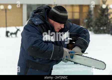 A manual file worker sharpens a chainsaw chain Stock Photo
