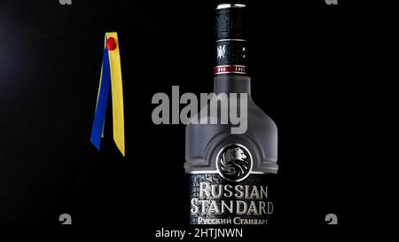 NORWALK, CT, USA - FEBRUARY 28, 2022: Russian Standard vodka with Ukrainian flag colors behind on black background Stock Photo