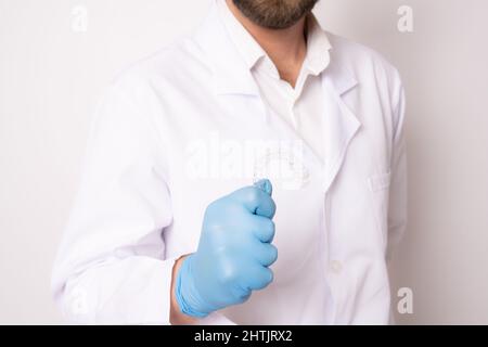 Dentist doctor holding aligners and braces in hand. Dental care concept. Stock Photo
