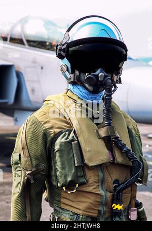 FIghter pilot in helmet and suit with oxygen mask in front of fighter jet. Stock Photo