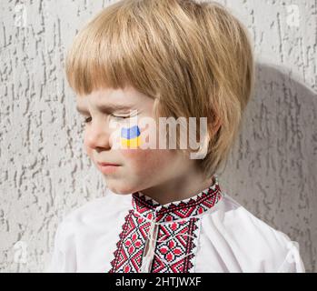 boy's face, the Ukrainian flag is painted on the cheek with yellow and blue colors. Russian invasion of Ukraine, no war. ask for help from the world c Stock Photo
