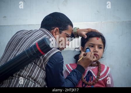 Kathmandu, Nepal. 01st Mar, 2022. A man paints a picture of lord Shiva on the face of a kid during the Shivaratri festival in Pasupatinath temple premises. Maha Shivaratri is one of the biggest Hindu festivals celebrated annually in honor of Lord Shiva and in particular, marks the night when Shiva performs the heavenly dance. Credit: SOPA Images Limited/Alamy Live News Stock Photo