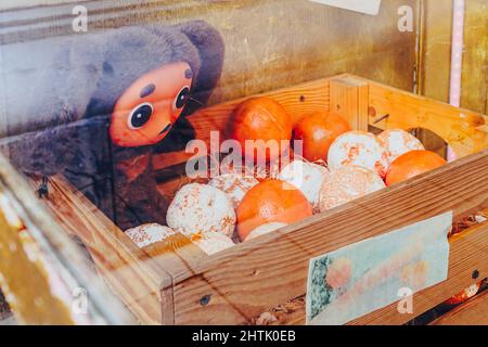 Toy eared Cheburashka and oranges in a wooden box behind glass. Cheburashka is a famous character in a children's cartoon. Stock Photo