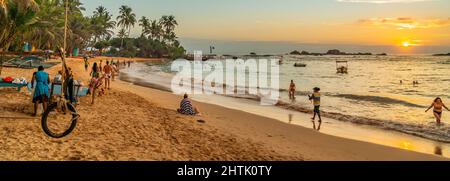 HIKKADUWA, SRI LANKA - DECEMBER 17.2021: Tourist walking along Turtle Beach during sunset Stock Photo