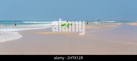 HIKKADUWA, SRI LANKA - JANUARY 22, 2022:Narigama beach at Hikkaduwa with surfer in the background Stock Photo