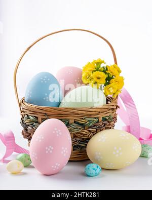 Colored easter eggs and flowers in a basket and on a white background Stock Photo