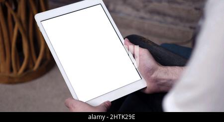 A tablet with empty white screen, close up on man hands while using an apple iPad with blank touch screen. Stock Photo