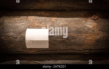 Toilet paper roll on holder against rustic wooden wall. Stock Photo