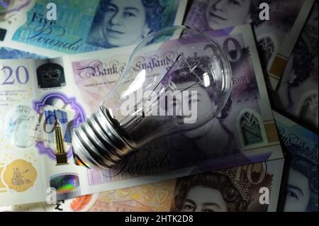 ELECTRIC LIGHT BULB WITH BRITISH CURRENCY RE ELECTRICITY BILLS COSTS PRICES ENERGY HOUSEHOLD BUDGETS ETC UK Stock Photo