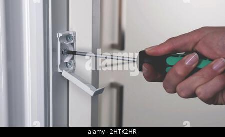 close up on hand using Screwdriver tool to driving screws background, socket screw of a aluminum window Stock Photo