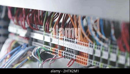 close up on multi colored electric wires and cables on electrical terminal blocks, power distribution wiring main panel, industrial concept background Stock Photo