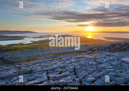 Sunset over typical Burren landscape of fissured limestone pavement overlooking Galway Bay near Ballyvaughan, The Burren, County Clare, Ireland Stock Photo