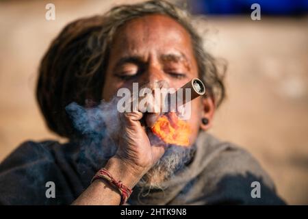 A Hindu holy man, or sadhu, smokes marijuana at the Pashupatinath Temple during the Mahashivaratri festival. Hindu Devotees from Nepal and India come to this temple to take part in the Shivaratri festival which is one of the biggest Hindu festivals dedicated to Lord Shiva and celebrated by devotees all over the world. Stock Photo