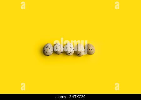 Five quail eggs on a yellow background with copy space Stock Photo