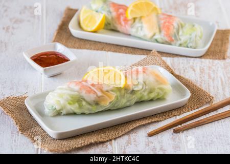 Two summer rolls with salad and prawns on a white wooden background, japanese, asian food Stock Photo